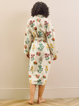 Person wearing a floral robe dressing gown standing against a plain wall.