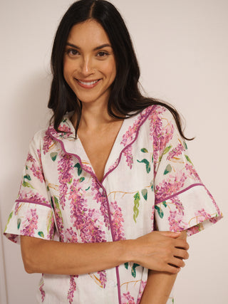 Model wearing white cotton voile oversized shortie pyjamas with pink wisteria print, short-sleeve shirt and elasticated waist shorts with pockets. detail