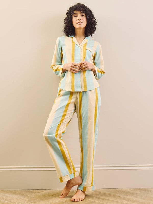 Woman wearing a striped pajama set against a beige wall.