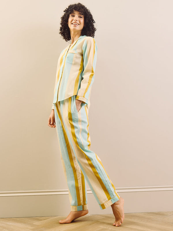 Woman wearing a striped pajama set standing in a room with a neutral background