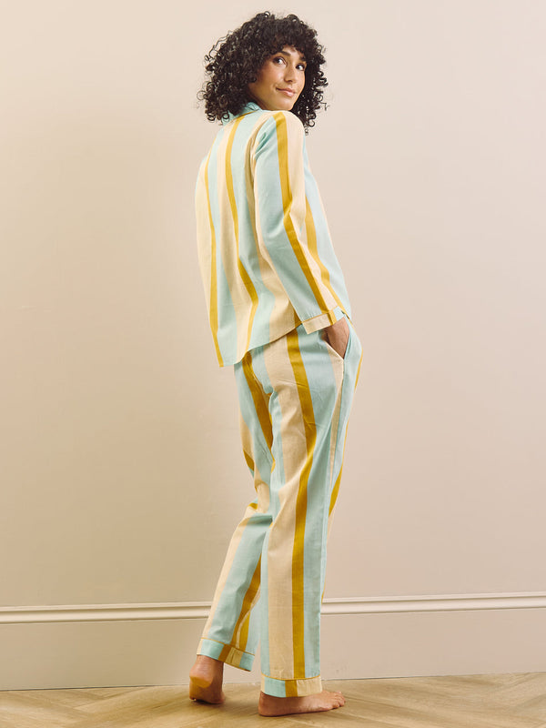 Woman wearing a striped outfit standing against a plain wall.