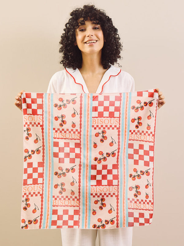 Woman holding a red and white checkered bandana with floral patterns on a beige background