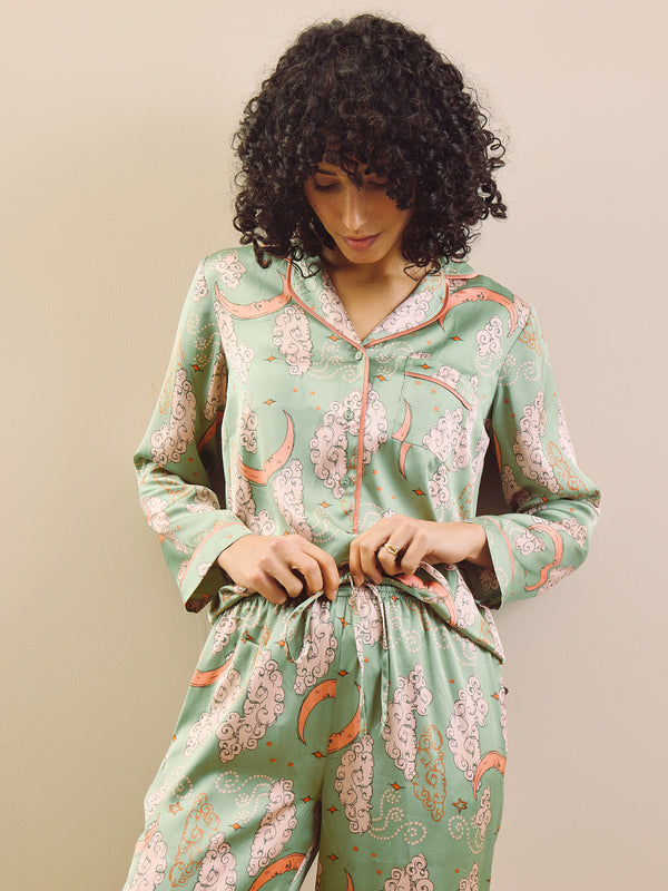 Woman wearing a green floral pajama set against a beige background