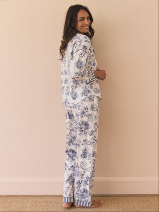 Woman wearing a floral pyjama set against a beige wall.