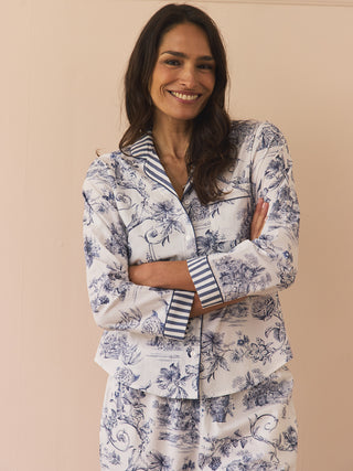 Woman wearing a navy and white toile floral pyjama set against a beige background