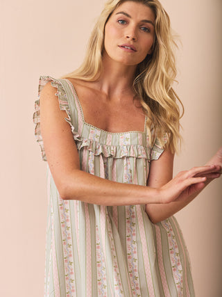 Woman wearing a striped nightdress with ruffled details on a beige background