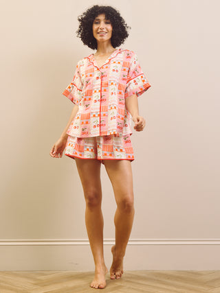 Woman wearing a cherry patterned pyjama set against a plain background