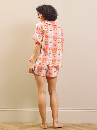 Person wearing a cherry patterned short pyjama set against a plain background
