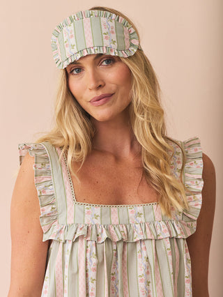 model wears and striped and floral night dress with frill square neck and matching eye mask against a pink background