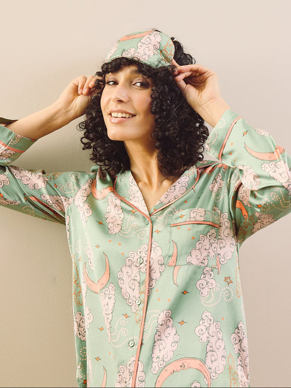 model wears sage green pyjamas and eye mask agains a beige background