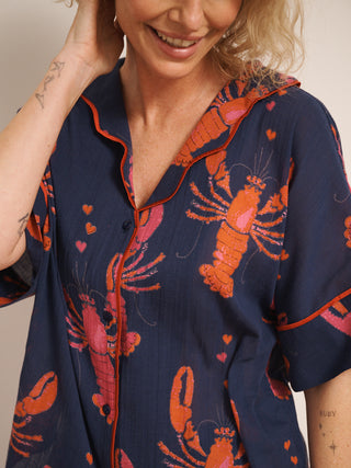 Model wearing navy gauze shortie pyjamas with a playful lobster and heart print, featuring a relaxed short-sleeve button-up shirt and matching shorts. print detail