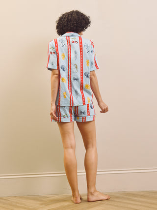 Person wearing a patterned pyjama set against a beige wall.