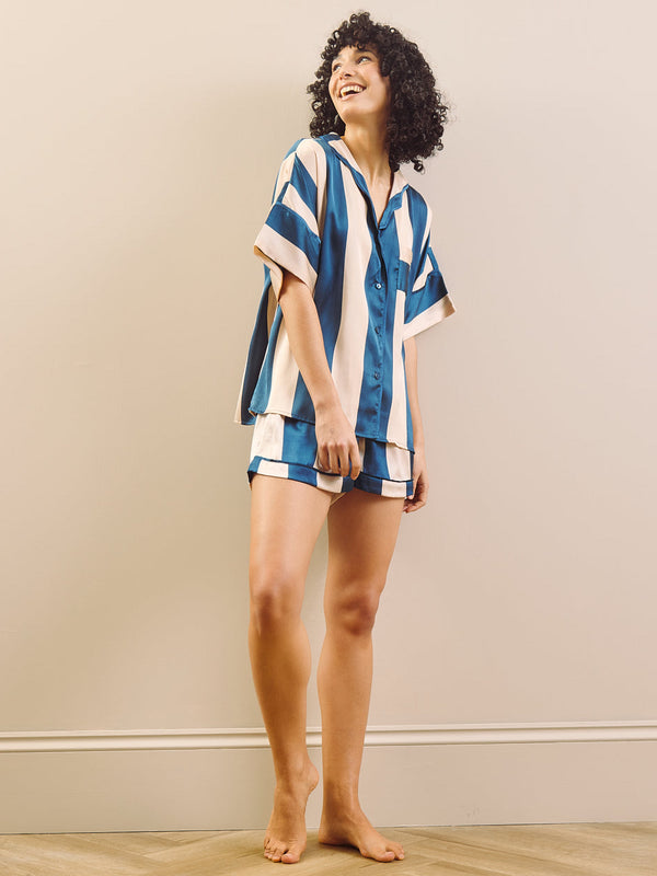 Woman wearing a blue and champagne striped pyjamas against a beige background