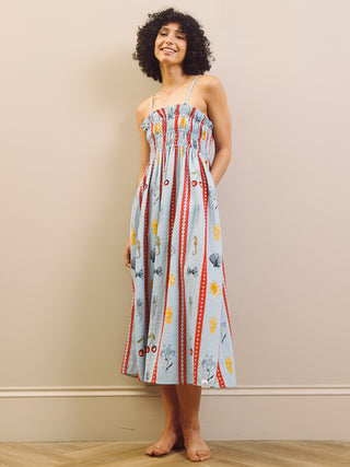 Woman wearing a colorful patterned night dress against a beige wall.