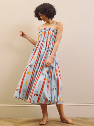 Woman wearing a colorful nightdress with a pattern of various items on a plain background