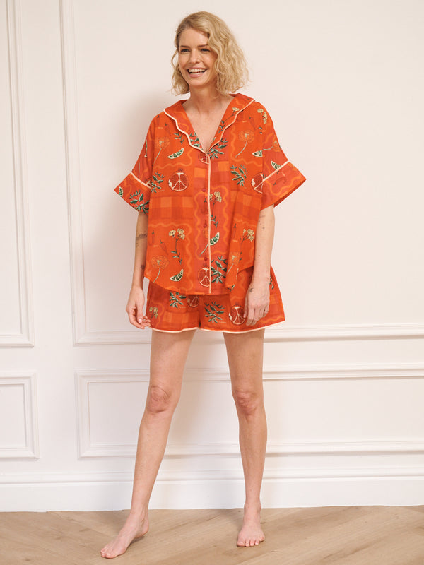 Model wearing women’s rust cotton gauze oversized shortie pyjamas with short-sleeve button-up top and matching shorts, featuring a spicy recipe print.