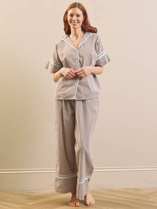Model wears Brown Gingham check pyjama set against a beige background. 