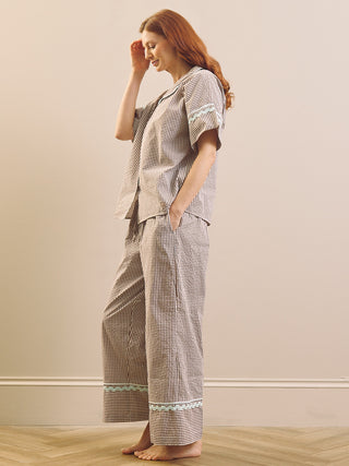 Model wears Brown Gingham check pyjama set against a beige background. side shot