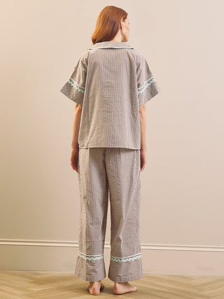 Model wears Brown Gingham check pyjama set against a beige background. Back shot