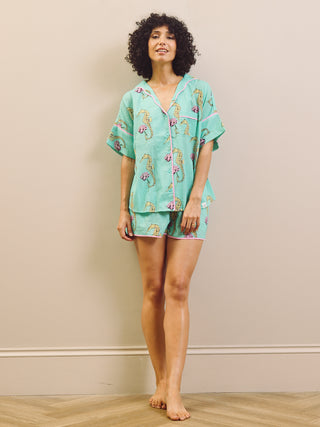 Woman wearing a light blue pyjama set with a seahorse pattern on a beige background.