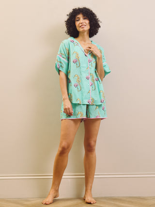 Woman wearing a light blue pyjama set with a seahorse pattern on a beige background