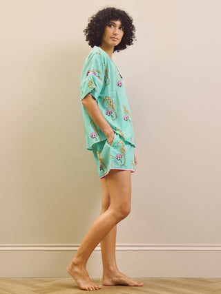 Woman wearing a light blue pyjama set with a seahorse pattern on a beige background