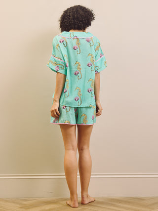 Woman wearing a light blue pyjama set with a seahorse pattern on a beige background