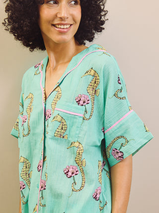 Woman wearing a light blue pyjama set with a seahorse pattern on a beige background