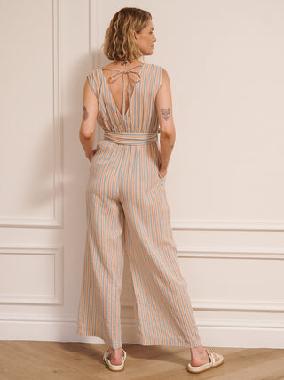 Model wearing women’s cotton gauze cross-body jumpsuit with baby pastel stripe, featuring a wrap front bodice, tie waist and wide-leg trousers. back detail