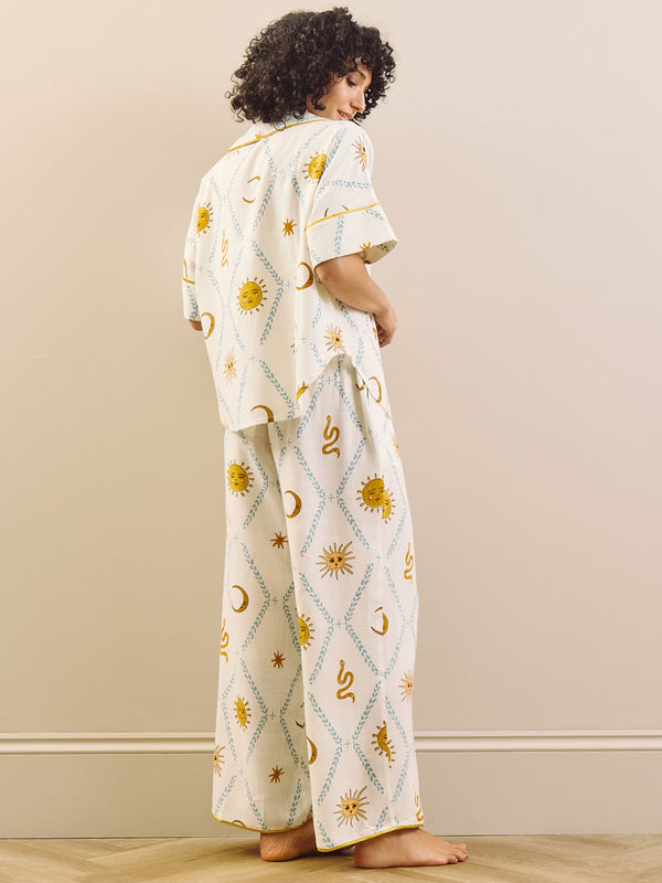 Woman wearing a white pyjama set with sun and moon patterns in a minimal indoor setting