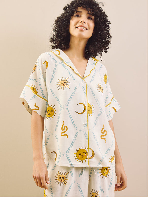 Woman wearing a white pyjama set with celestial pattern on a beige background