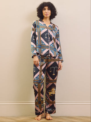 Woman wearing a celestial patterned satin pyjamas standing against a plain wall.