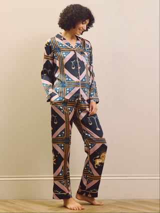 Woman wearing a celestial patterned satin pyjamas standing against a plain wall.