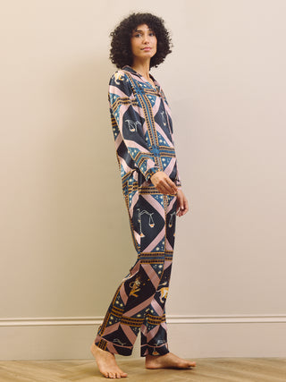 Woman wearing a celestial patterned satin pyjamas standing against a plain wall.
