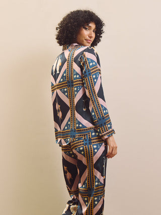 Woman wearing a celestial patterned satin pyjamas standing against a plain wall.