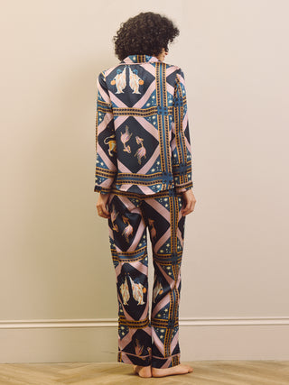 Woman wearing a celestial patterned satin pyjamas standing against a plain wall.