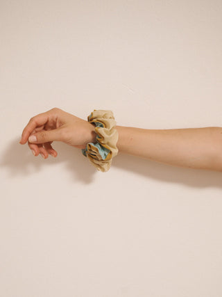 Cotton voile scrunchie in oatmeal rainbow stripe print worn on a wrist, made from lightweight striped fabric.