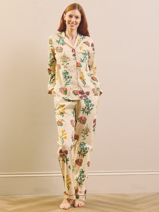Model wears wallpaper floral print pyjamas on a neutral wall and wooden floor. 