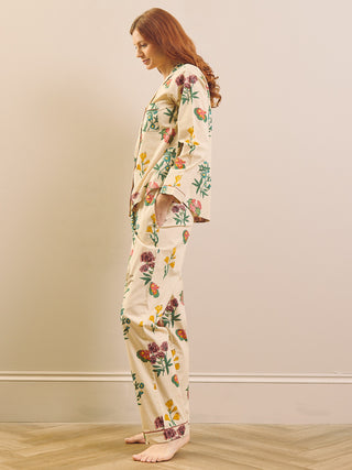 Model wears wallpaper floral print pyjamas on a neutral wall and wooden floor. 