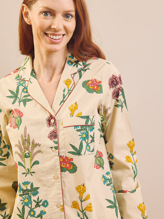 Model wears wallpaper floral print pyjamas on a neutral wall and wooden floor. Detail shot.