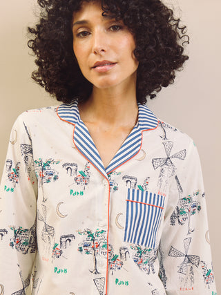 Woman wearing a navy and white Paris print pyjama with stripes set against a plain background