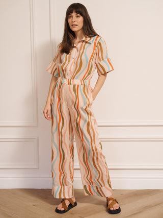 model  wearing a cotton voile smart collar jumpsuit in oatmeal Rainbow Waves print with short sleeves and wide legs