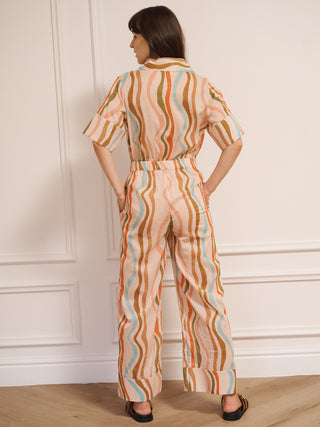 model  wearing a cotton voile smart collar jumpsuit in oatmeal Rainbow Waves print with short sleeves and wide legs. back detail