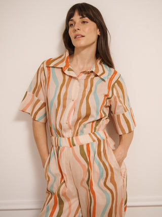 model  wearing a cotton voile smart collar jumpsuit in oatmeal Rainbow Waves print with short sleeves and wide legs