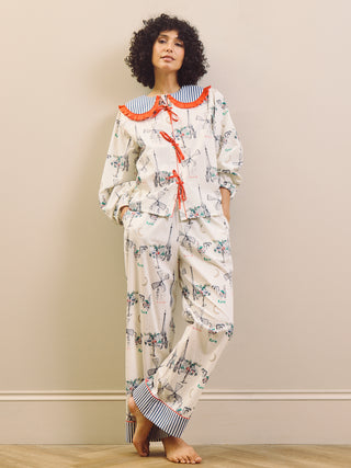 Woman wearing a Paris themed printed pyjama set with a large collar with red frill against a beige background