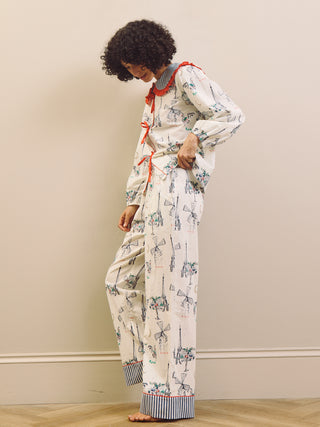 Woman wearing a Paris themed printed pyjama set with a large collar with red frill against a beige background
