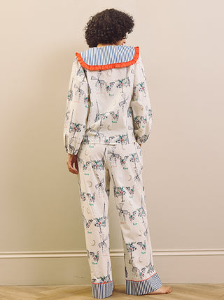 Woman wearing a Paris themed printed pyjama set with a large collar with red frill against a beige background