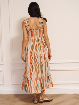 Model wearing Their Nibs linen mix ruched body midi dress in oatmeal rainbow waves print, back view