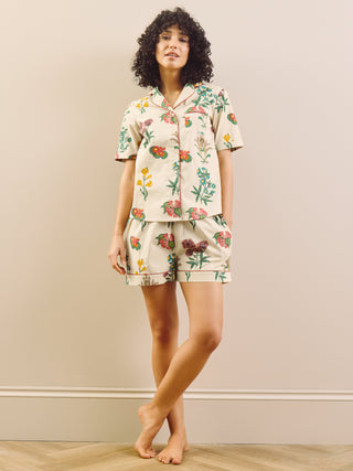 Woman wearing a floral pyjama set in a room with a plain wall.