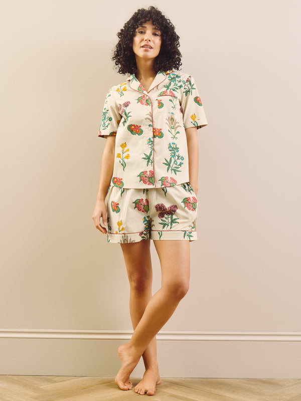 Woman wearing a floral pyjama set in a room with a plain wall.